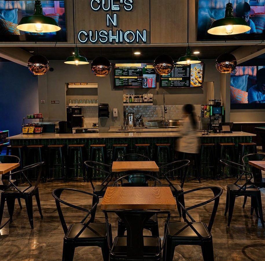 Bar counter with stools and menu screens at Cue's N Cushion