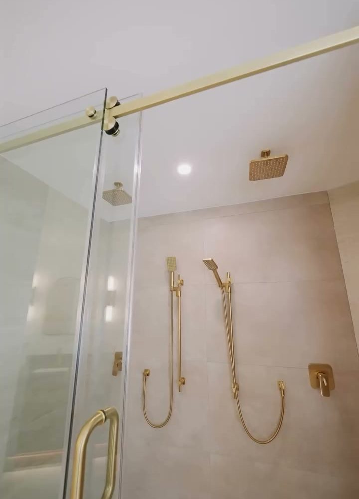Glass shower with brushed brass fixtures and large-format tile in the Port Moody ensuite