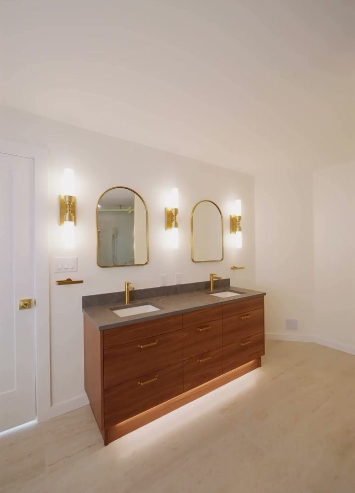 Brushed brass wall sconces above the walnut vanity in the Port Moody ensuite